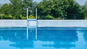 A clear swimming pool with a metal ladder and a clear blue sky in the background. - i castagni (Vigevano)