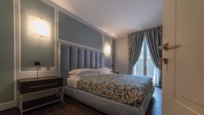 A bedroom with a bed, bedside tables, a lamp, and a window with curtains. - i castagni (Vigevano)