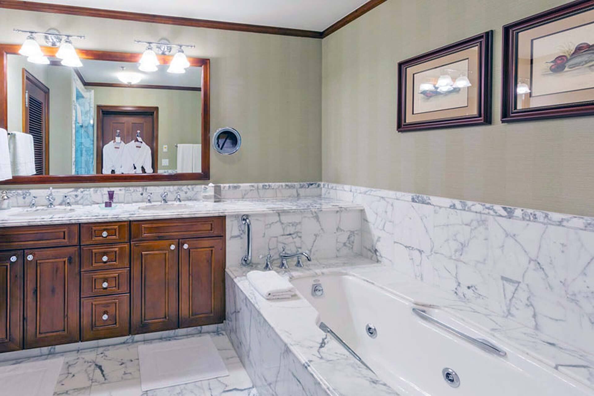 A bathroom with a marble vanity, a bathtub, and a large mirror.