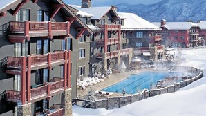 Un hôtel doté de nombreux balcons, d’une piscine et offrant une vue sur des montagnes enneigées.