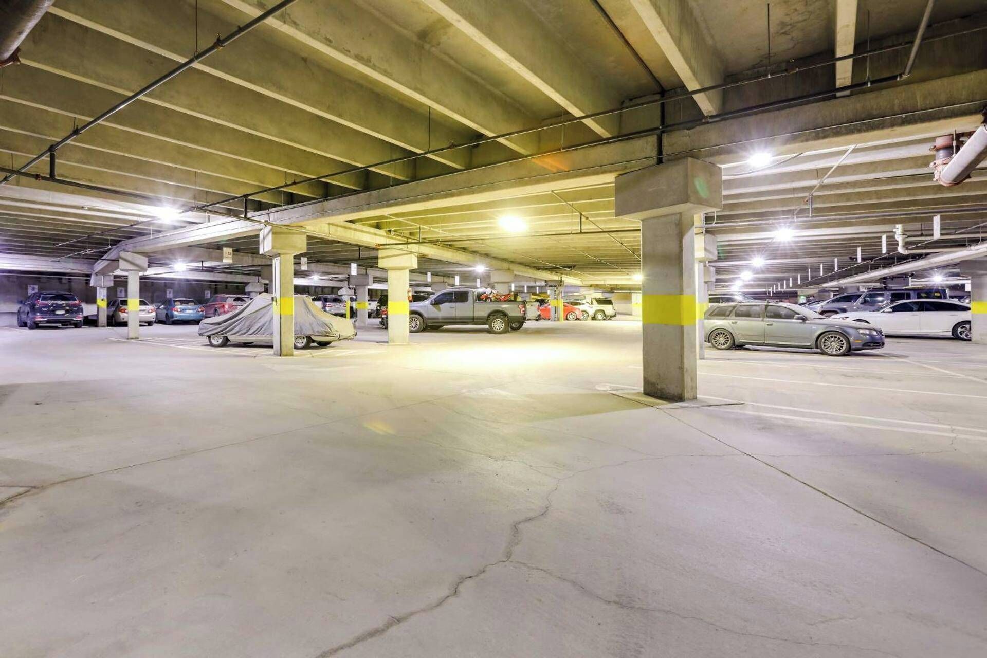 A multi-level parking garage with concrete pillars and overhead lighting.