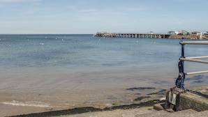 A pier extending into calm waters with a clear sky. - Oaks (Swanage)
