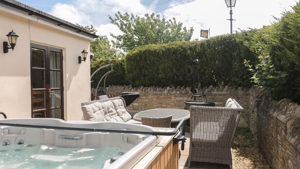 A hot tub with wicker furniture and a stone wall. - The Farmhouse (Swanage)