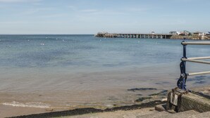 A pier extending into calm waters with a clear sky. - The Farmhouse (Swanage)