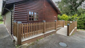 Une cabane en bois dotée d’une terrasse en bois et d’une entrée clôturée.
