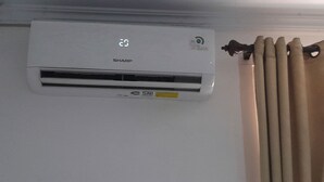 A wall-mounted air conditioner with a digital display, a brand name, and a model number.