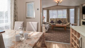 A cozy living room with a sofa, a coffee table, and a dining area with a table set for two.