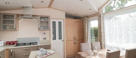 A modern kitchen with a central island, wooden cabinets, and a dining area with a table and chairs.