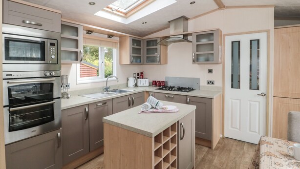 A modern kitchen with built-in appliances, a central island, and a skylight.