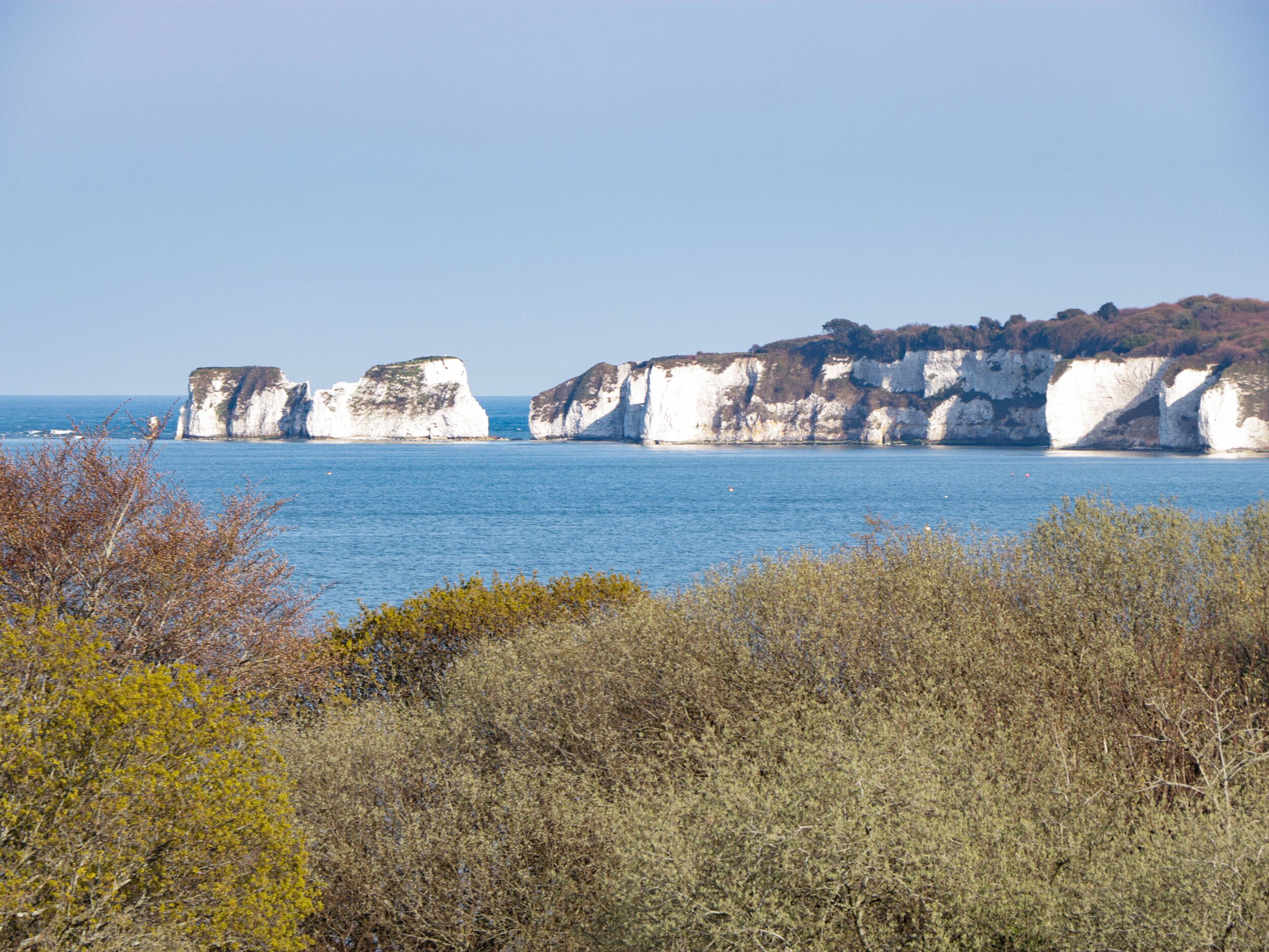 A coastal landscape with white cliffs and a clear blue sea.