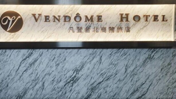 Uma receção de mármore com o texto "VENDOME HOTEL" e um logótipo.