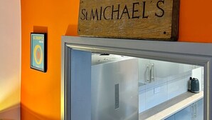 A kitchen area with a stainless steel refrigerator, a wooden sign above it, and a framed picture on the wall. - St Michael`s House Contractors, Families, Groups (Nottingham)