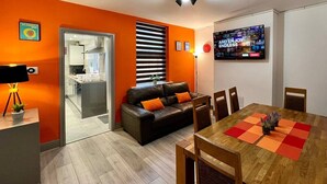 A modern living room with a sofa, dining table, and a television. - St Michael`s House Contractors, Families, Groups (Nottingham)