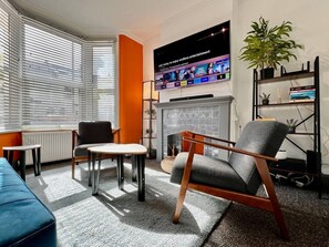 Ett modernt vardagsrum med en öppen spis, en tv som är monterad på väggen och en bokhylla.