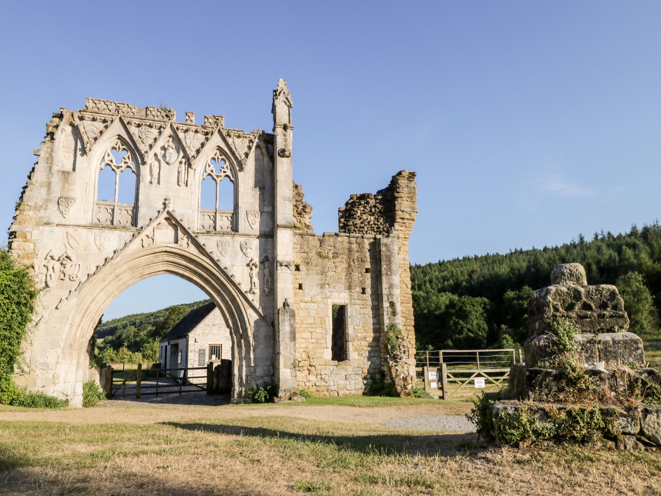 A historic stone archway with intricate carvings, leading to a building with a small entrance.