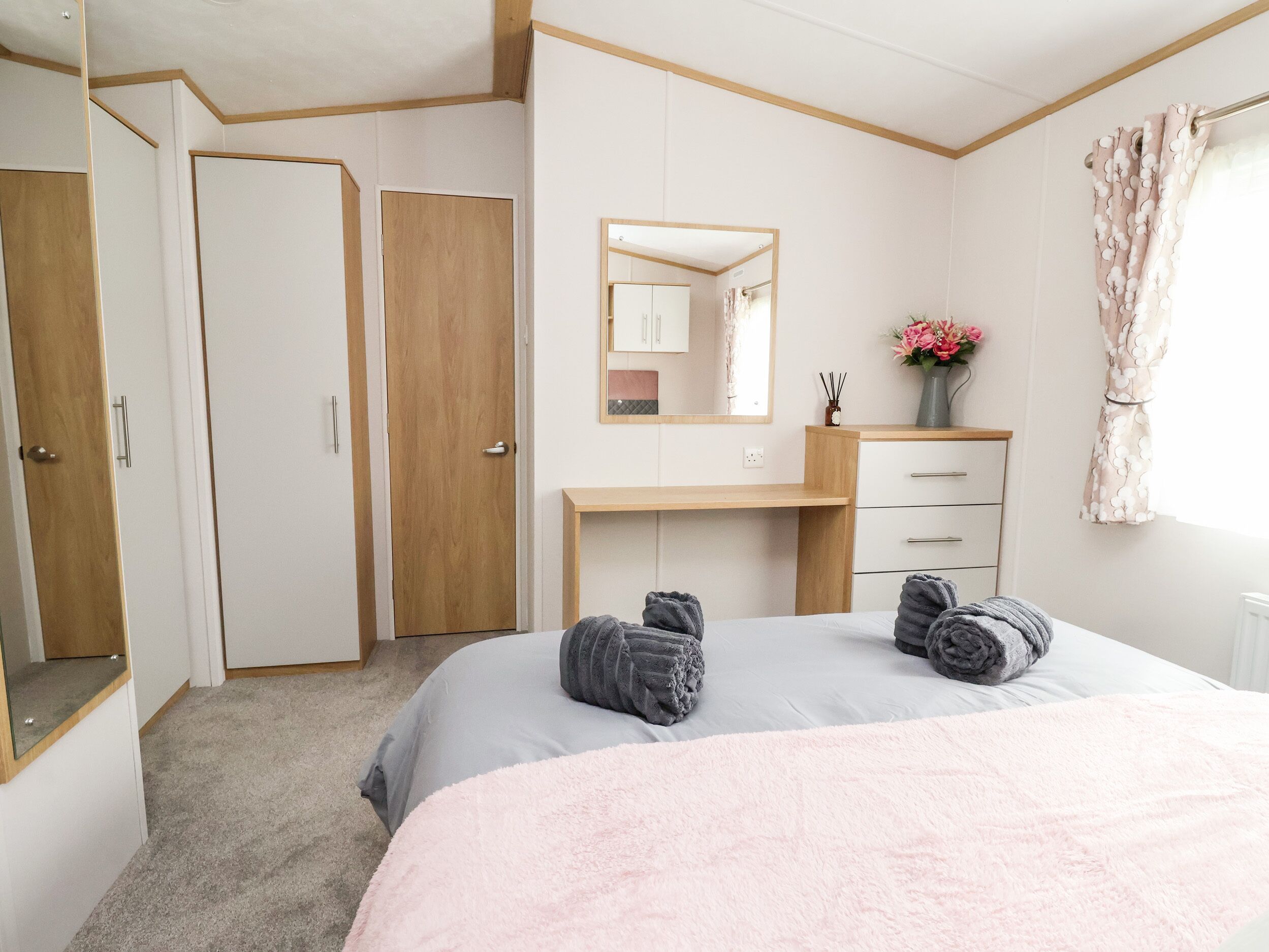 A bedroom with a bed, a dresser, a mirror, and a door.