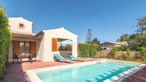 Un área junto a la piscina con piscina, sillas de descanso y una mesa con sillas.