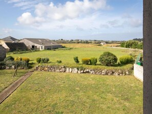 A rural property with a stone wall, a grassy field, and a building with a sloped roof.