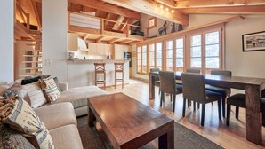 Un interior acogedor con un comedor de madera, un sofá con cojines estampados y una cocina con armarios de madera.