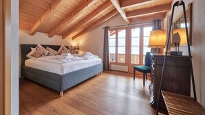 Un dormitorio con cama, escritorio, silla y un ventanal grande.
