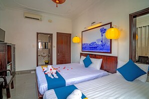 A hotel room with two beds, a wooden headboard, a mounted painting, and a mounted television. - Hoi An Viet House Homestay (Da Nang)