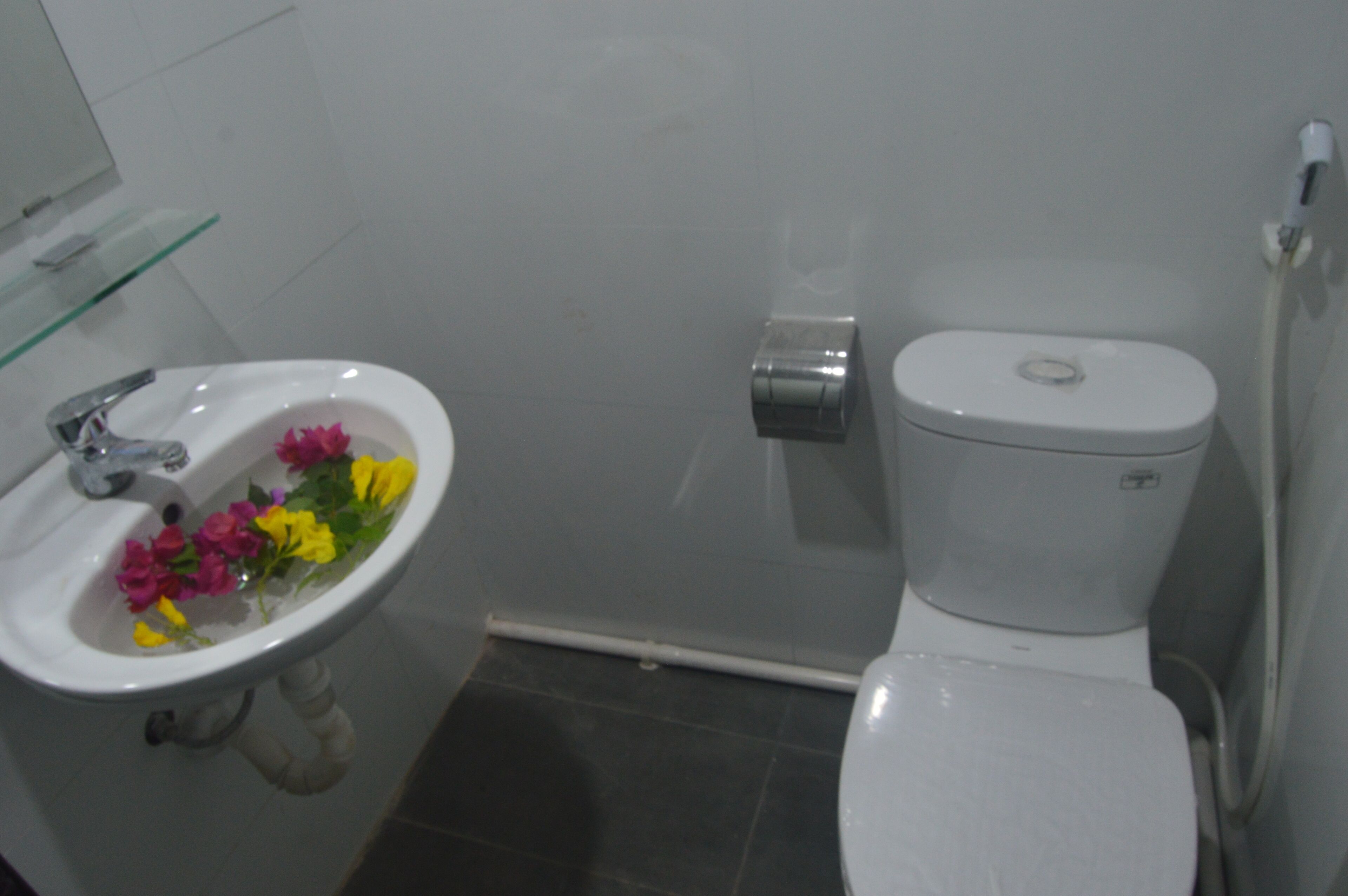 Un baño con lavamanos blanco, inodoro y repisa de vidrio.