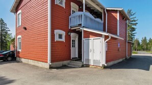 Un bâtiment en bois rouge avec un porche blanc et un petit balcon.