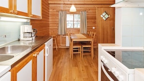 Een gezellig keuken in blokhutstijl met houten wanden, een eettafel en eenvoudige apparatuur.
