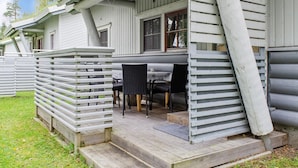 Een houten hut met een veranda, zitplaatsen buiten en een kleine tafel.