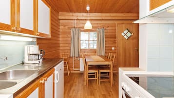 A compact kitchen with wooden cabinets, a dining table, and a built-in oven.