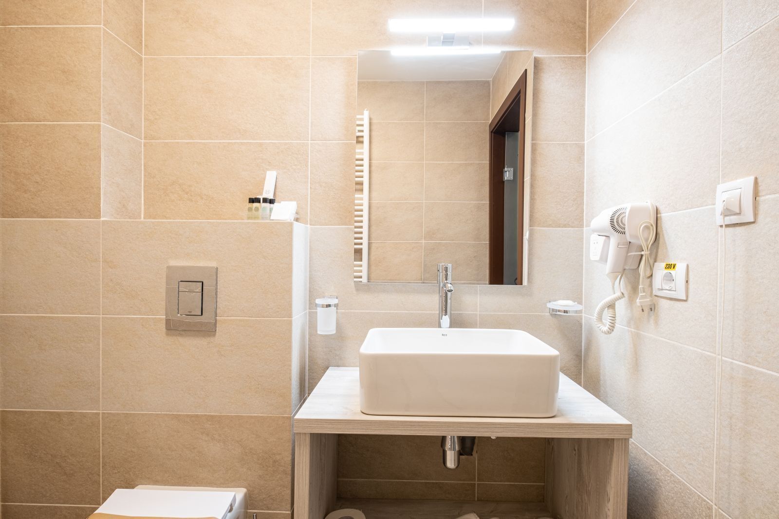A modern bathroom with a large sink, a mirror, a towel rack, and a hairdryer.