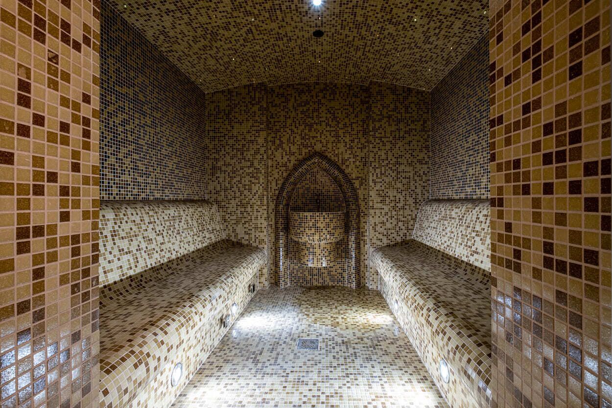 A tiled corridor with benches and an arched doorway.