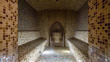 A tiled corridor with benches and an arched doorway.
