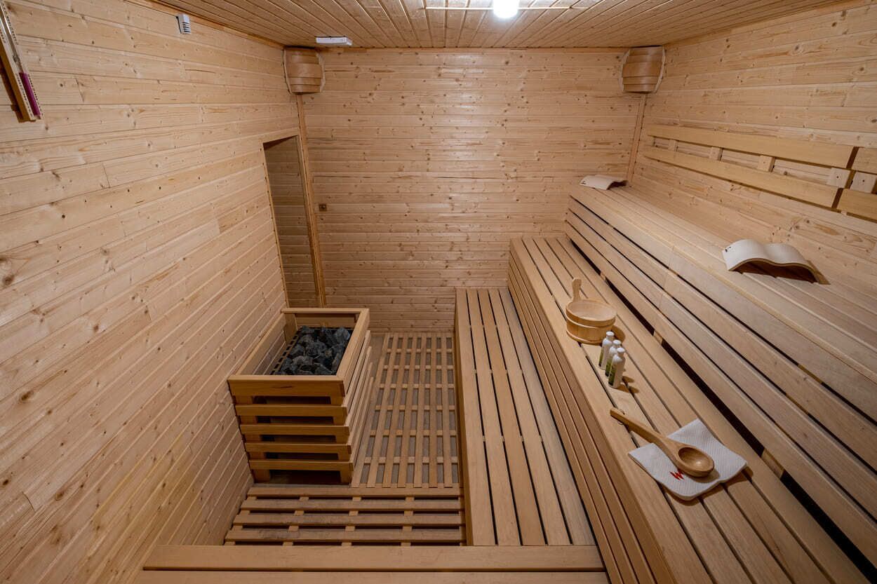 A wooden sauna with benches, a wooden bench, a wooden bench with a towel, and a wooden bench with a towel and a cup.