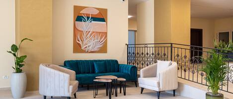 A modern living room with a teal sofa, two white armchairs, a coffee table, and a large abstract painting on the wall.
