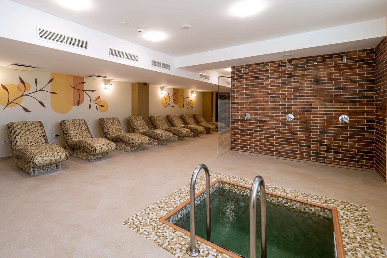 Zona de spa con piscina, sillas reclinables y pared de ladrillo.