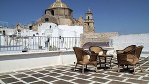 Una terrazza sul tetto con sedie in vimini e vista su un edificio storico con cupola e campanile.