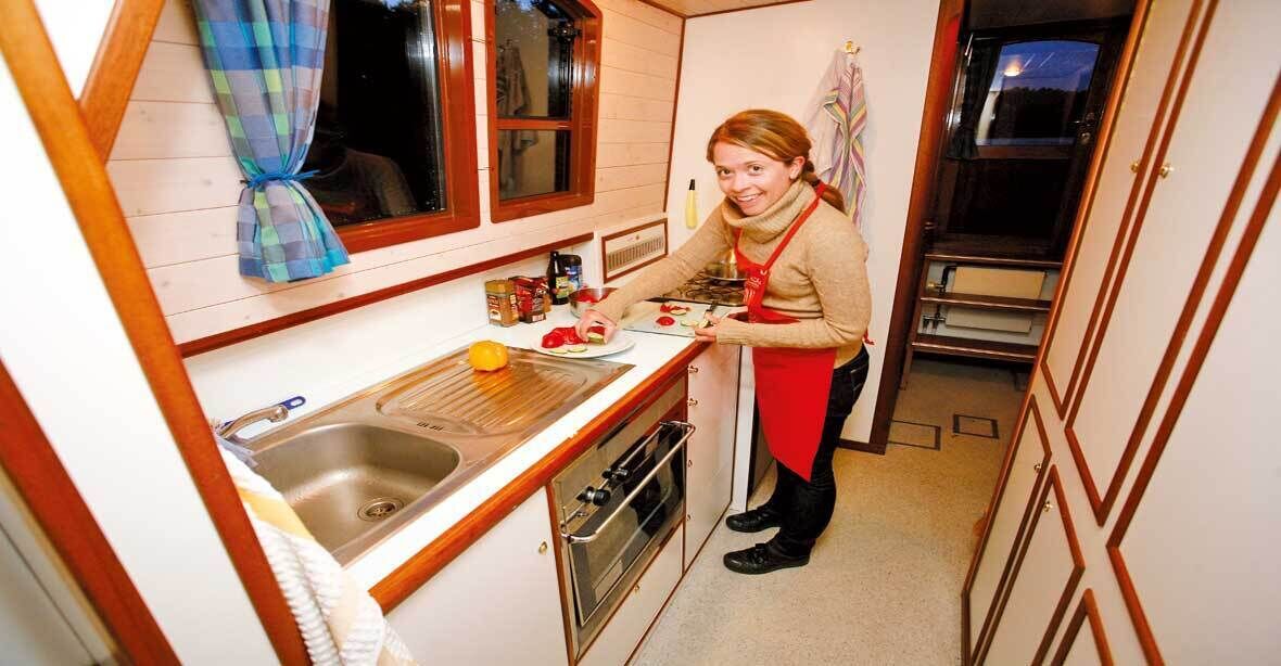 Une cuisine de taille réduite, équipée d’un évier, d’une cuisinière et de placards.