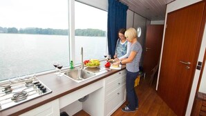 A kitchen with a view of a lake, a sink, and a stove. - Boats & Yachts at Zehdenick Harbor by Kuhnle‑Tours  (Zehdenick)