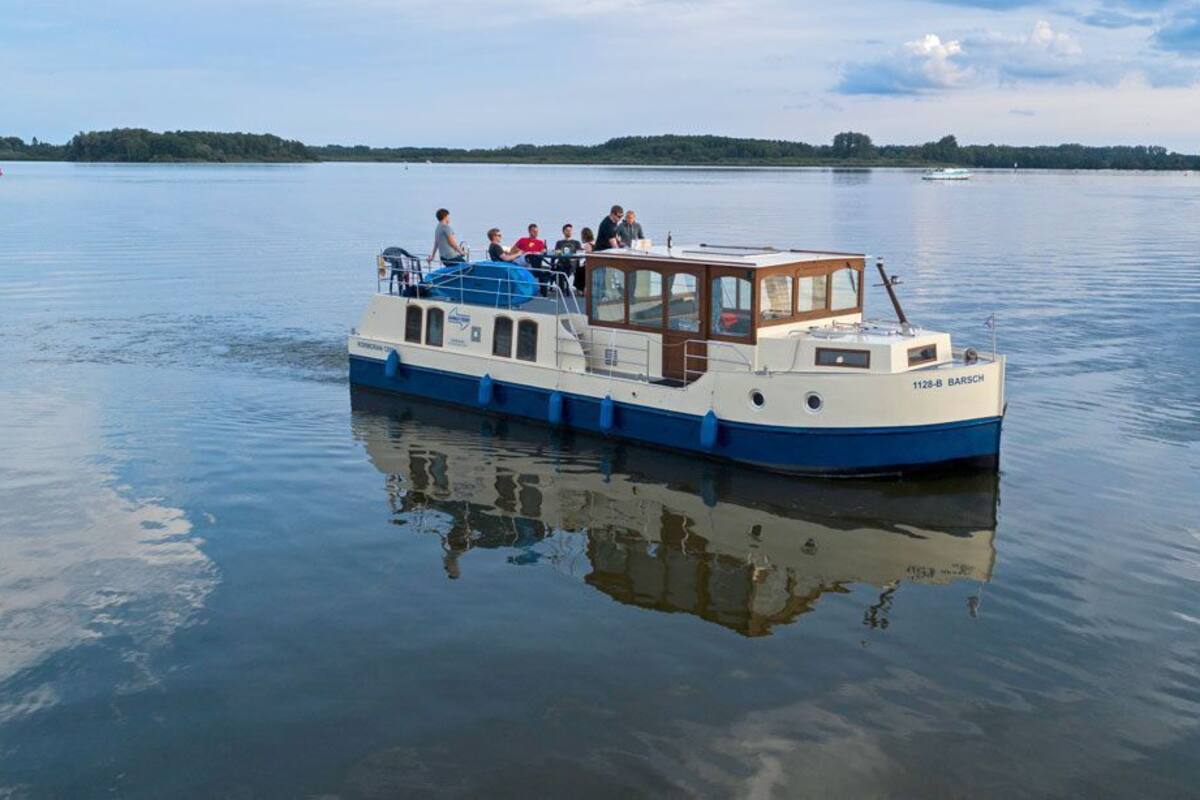 A boat with passengers, calm water, and a distant shoreline.