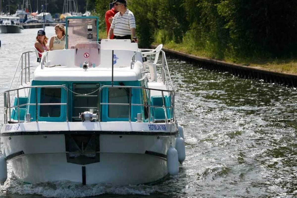 A boat with a cabin and a covered area, moving on a waterway.