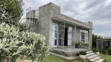 A modern house with a concrete exterior, large windows, and a small outdoor staircase.