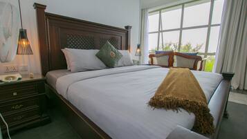 A neatly made bed with a brown throw blanket, a wooden headboard, and a nightstand with a lamp.