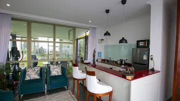 A modern kitchen with a red countertop, bar stools, and a large window.