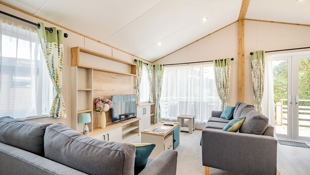 A modern living room with a sofa, armchair, TV, and a small table. - Hot Tub Lodge 3 Pet Friendly (Kirkcudbright)