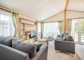 A modern living room with a sofa, armchair, TV, and a small table.