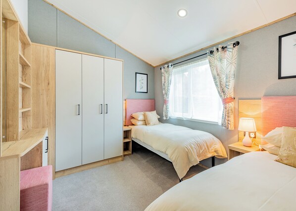 A bedroom with a bed, a wardrobe, a bedside table with a lamp, and a window with curtains.