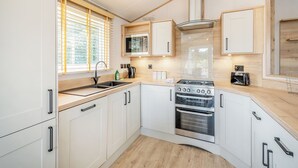 Una cocina moderna con armarios blancos, una estufa de acero inoxidable, un microondas y un lavaplatos.