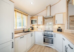 Una cocina moderna con armarios blancos, una estufa de acero inoxidable, un microondas y un lavaplatos.
