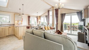 A spacious living area with a sofa, dining table, and kitchen area. - Country and modern cladded lodge with sea views. (Kirkcudbright)